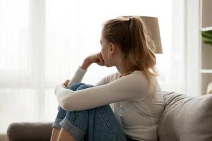 Side view young woman looking away at window sitting on couch at home. Frustrated confused female feels unhappy problem in personal life quarrel break up with boyfriend or unexpected pregnancy concept - Image credit: fizkes | stock.adobe.com