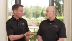 Two men, one with brown hair, is gesturing towards a bald man in conversation. They are both wearing Inizio Engage t-shirts.