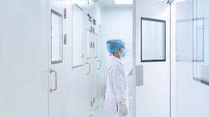 Unidentified microbiologist is open the cleanroom door to enter the room in clean area of microbial laboratory in pharmaceutical factory, concept of science, healthcare and safety operation. | Image Source: ©Sukjai Photo - stock.adobe.com