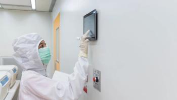 A scientist in sterile coverall gown using a daily checklist check the cleanroom condition status in laboratory. Cleanroom facility. | Image Credit: ©warut – Stock.Adobe.com