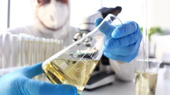 megaflop/Stock.adobe.com - chemical lab doing chemical testing, lab personnel holding flask with yellow liquid