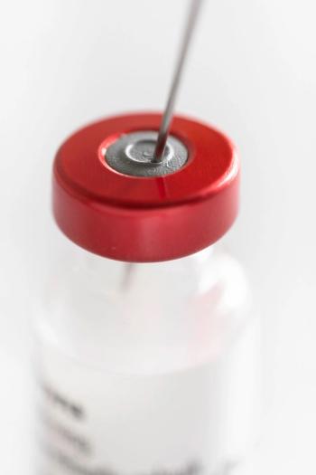 Needle of a syringe protrudes through the rubber cap of a vaccine vial with red cap. Focus on the rubber stopper, shallow depth of field |Image Credit: © Henk Vrieselaar – stock.adobe.com