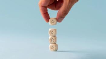 hand placing a block on top of a series of blocks with stars