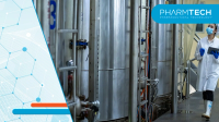 Quality inspector walking through processing area with stainless tanks and tablet | Image Credit: ©Surachai -stock.adobe.com