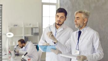Two scientists in white lab coats and gloves developing new effective drug together. Serious young student trainee with clipboard making notes and talking to senior professor in university laboratory | © Studio Romantic. - stock.adobe.com