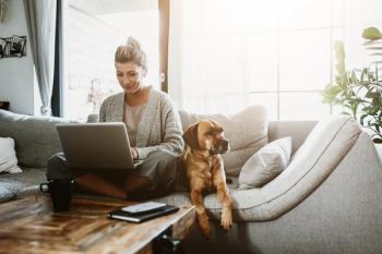 woman sits on couch with laptop and dog | © MT-R - stock.adobe.com