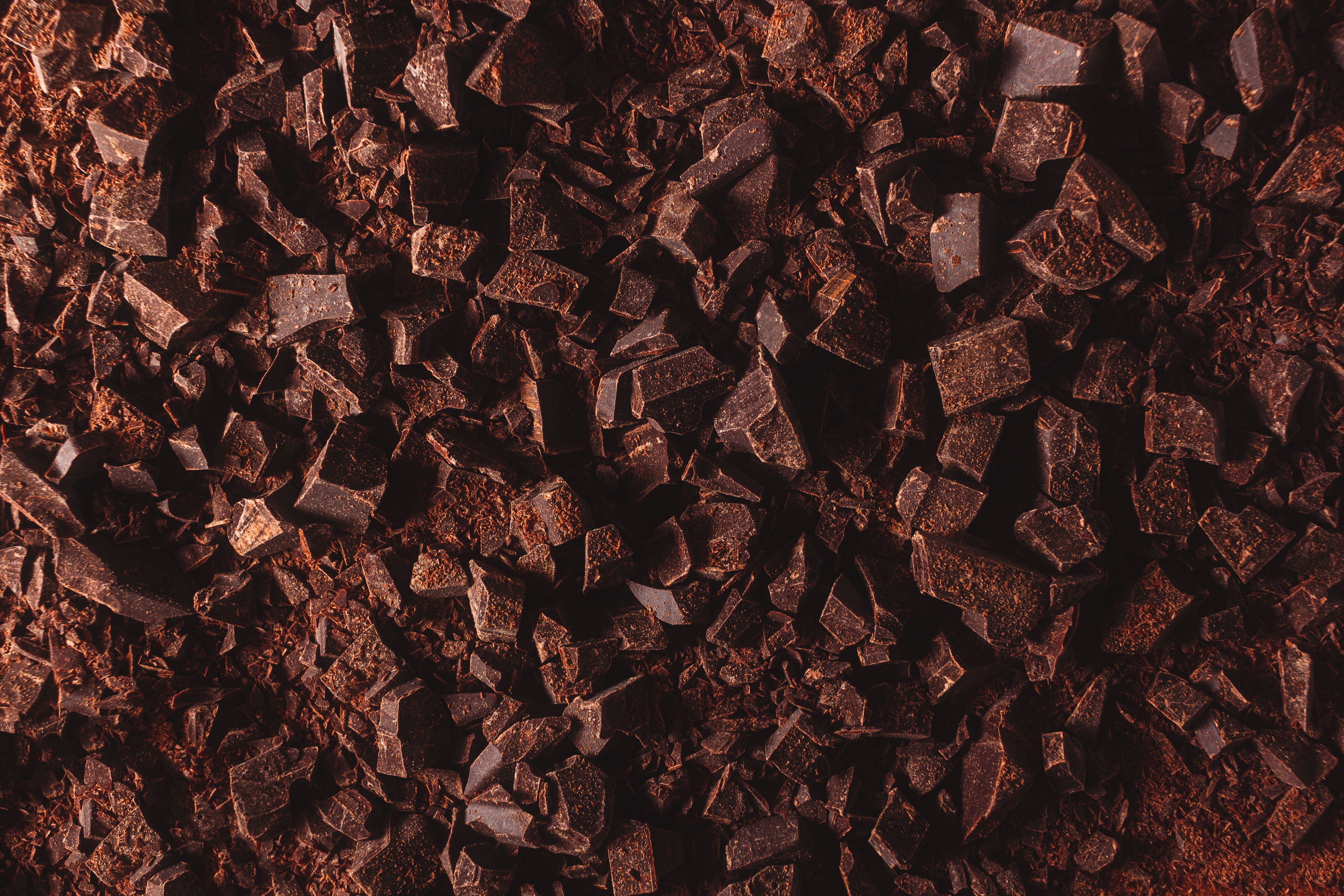 Flat lay view of dark chocolate chopped. Texture of cracked chocolate with copy space. | Image Credit: © Elena Uve - stock.adobe.com