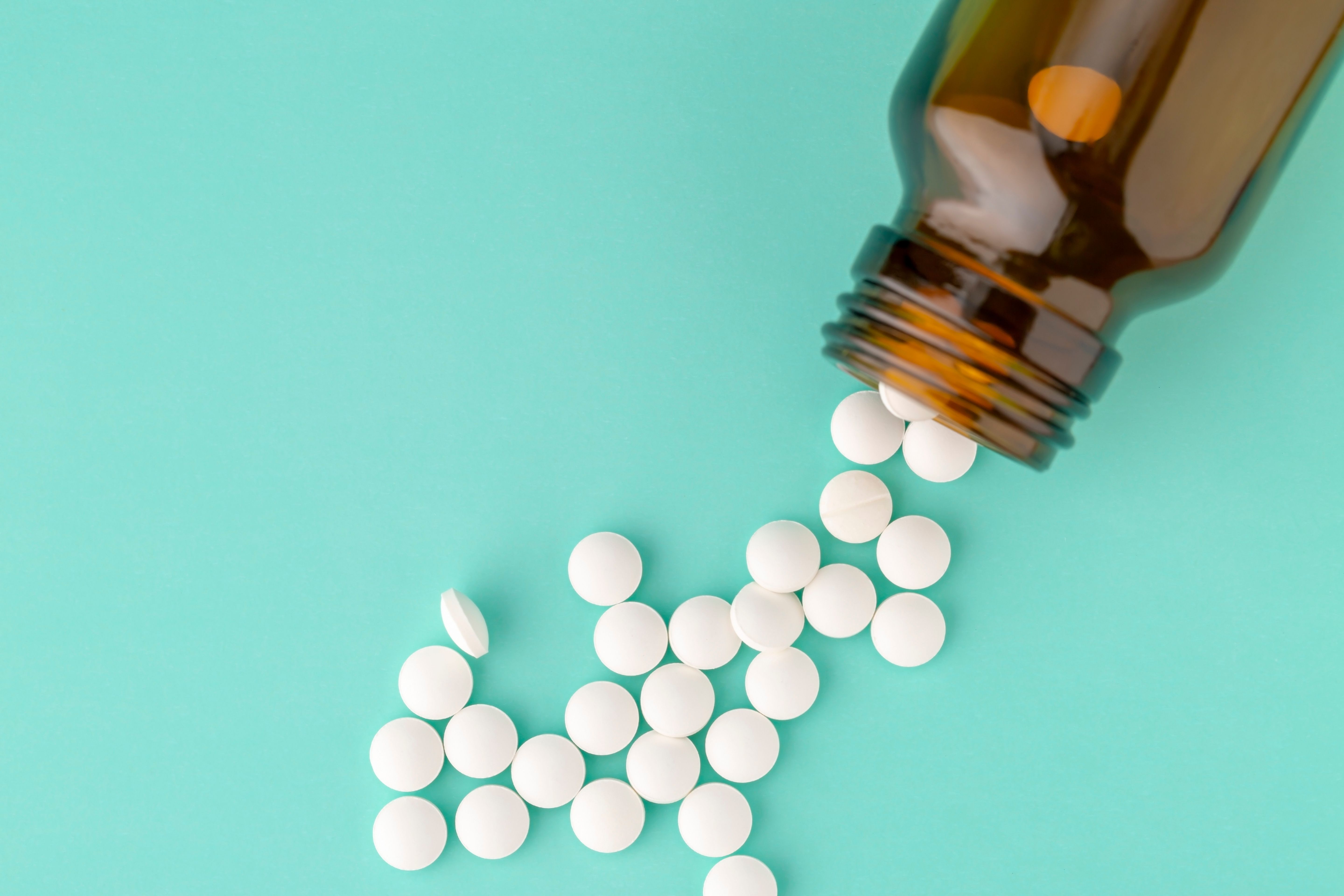 White round tablets scattered near glass bottle of pills | Image Credit: © ironstealth - stock.adobe.com