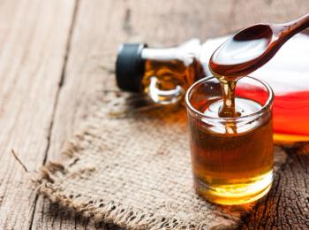 Maple syrup in glass bottle on wooden table | Image Credit: © showcake - stock.adobe.com