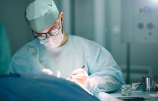 Work of the surgeon in the hospital operating room. Concentrated doctor with glasses. | Image Credit: © velimir - stock.adobe.com