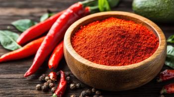 A bowl filled with vibrant chili powder accompanied by fresh chili peppers, showcasing rich colors and textures typical of spicy ingredients. Generated with AI. | Image Credit: © Diffin - stock.adobe.com