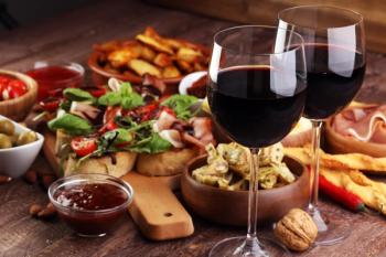 Italian antipasti wine snacks set. Cheese variety, Mediterranean olives, pickles, Prosciutto di Parma, tomatoes, artichokes and wine in glasses | Image Credit: © beats_ - stock.adobe.com