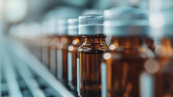 A close-up shot displays a neatly aligned row of amber-colored glass bottles with silver caps on a conveyor belt, presumably in a pharmaceutical or chemical factory setting. | Image Credit: © svastix - stock.adobe.com
