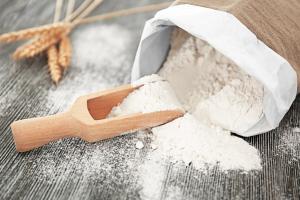 Bag and scoop with wheat flour on wooden table | Image Credit: © Africa Studio - stock.adobe.com.