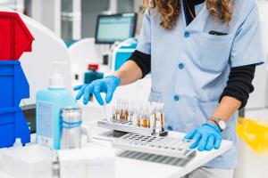 Unrecognizable healthcare worker in lab coat processes blood tests with machinery for simultaneous analysis in a clinical setting | Image Credit: © Koldo_Studio - stock.adobe.com.