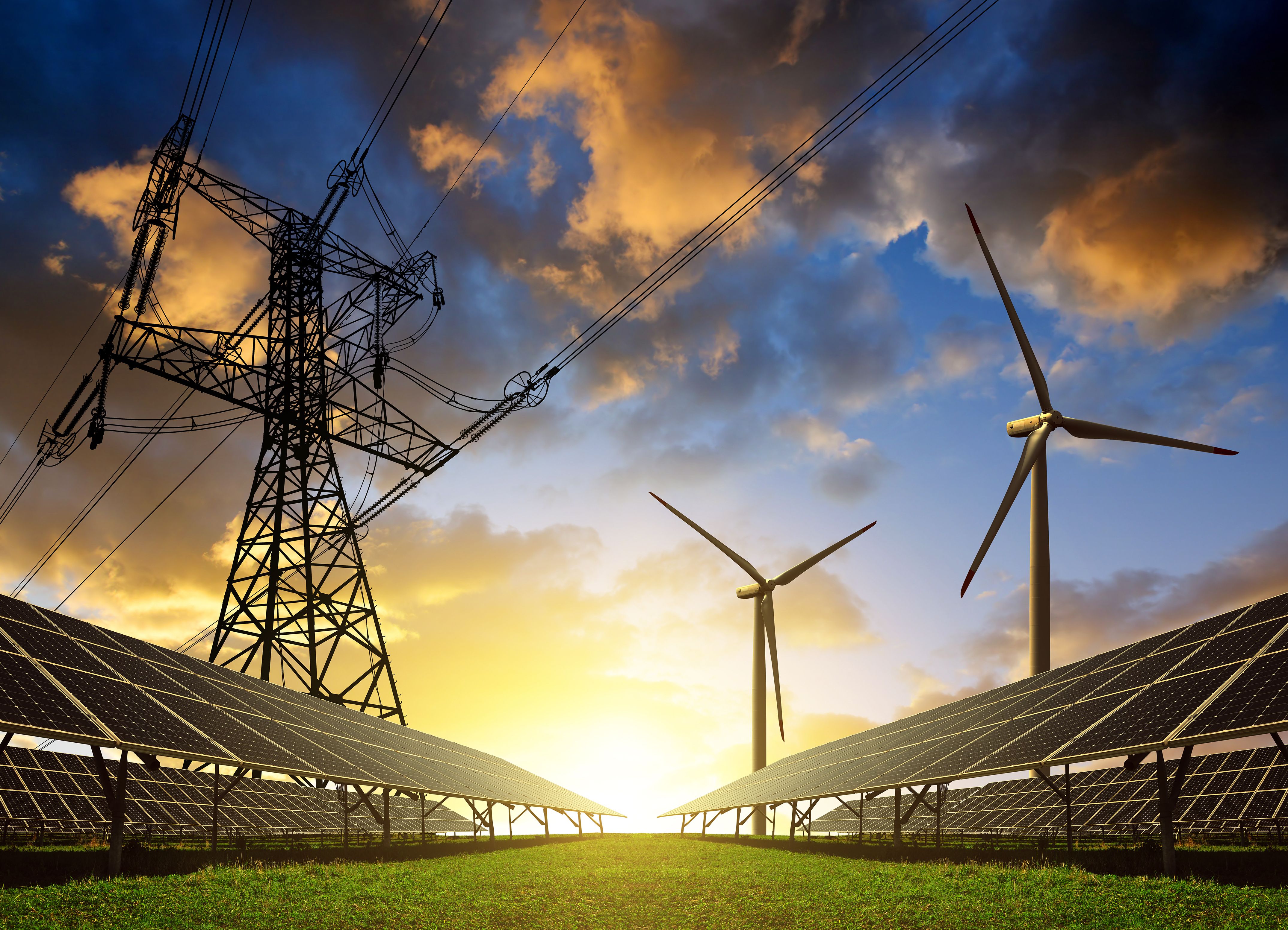 Solar panels with wind turbines and electricity pylon at sunset. Clean energy concept. | Image Credit: © vencav - stock.adobe.com.
