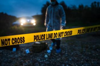 Forensic police investigator collecting evidence at the crime scene by the river in nature at night selective focus on police line tape. | Image Credit: © Miljan Živković - stock.adobe.com