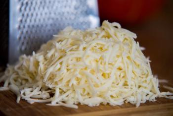 Shredded mozzarella cheese on a cutting board with a grater | Image Credit: © irontrybex - stock.adobe.com