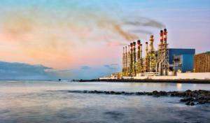 Sunrise over the water with a water desalination plant in the background