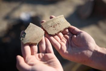 An archaeologist at an archaeological site shows fragments of ancient pottery in their hands. | Image Credit: © river34 - stock.adobe.com