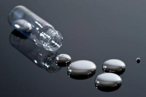 Mercury and glass container on a reflective surface.