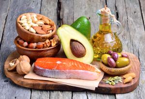 Selection of healthy fat sources on wooden background.
