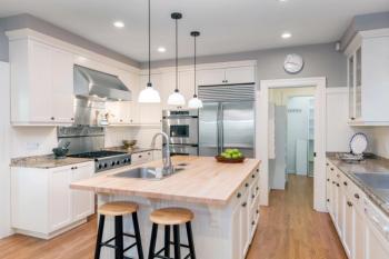 Amazing Luxury Kitchen Interior in white with wooden floor and kitchen island. | Image Credit: © coralimages -stock.adobe.com