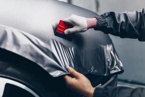 Car wrapping specialist putting vinyl foil or film on car. Selective focus. | Image Credit: © hedgehog94 - stock.adobe.com