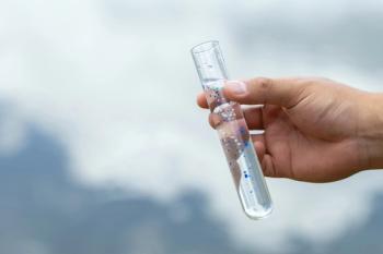 Microplastics. Male hands holding a test tube containing microplastic fragments and dirt on a lake. Plastic pollution and industrial waste management. environment. | Image Credit: © Pcess609 - stock.adobe.com
