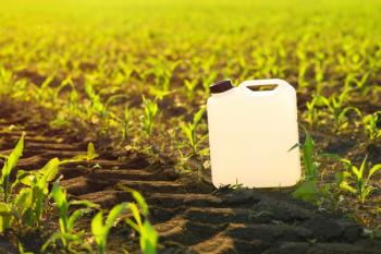 Blank white herbicide canister can in corn seedling field in springtime sunset | Image Credit: © Bits and Splits - stock.adobe.com