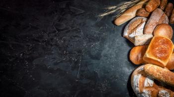 Assortment of fresh baked bread on dark background. White and rye bread, buns with copy place | Image Credit: © Andrii - stock.adobe.com