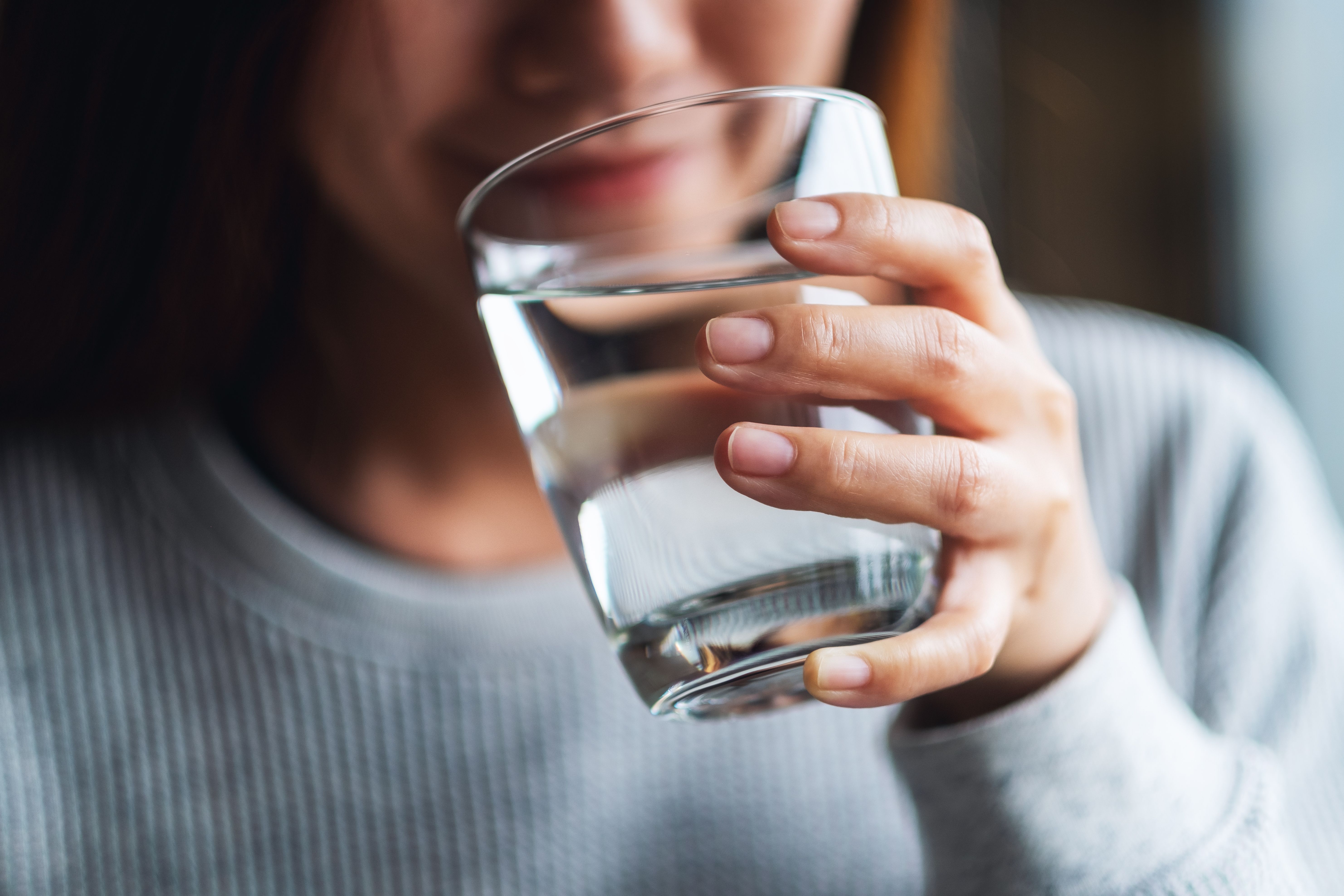 Closeup image of a young woman holding a glass of water to drink. | Image Credit: © Farknot Architect - stock.adobe.com