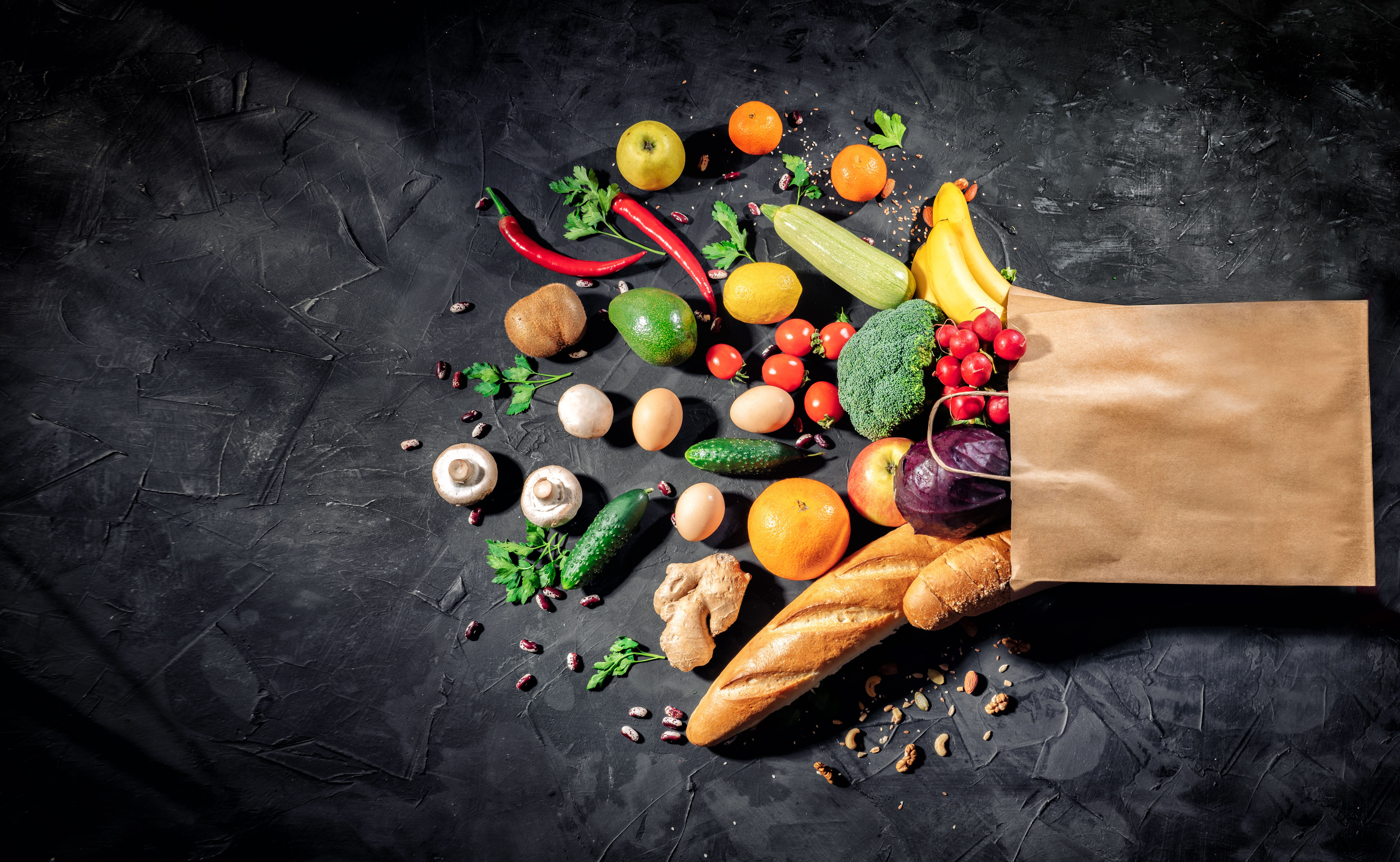 Healthy food in full paper bag of different products vegetables and fruits on dark background | Image Credit: © Storm - stock.adobe.com