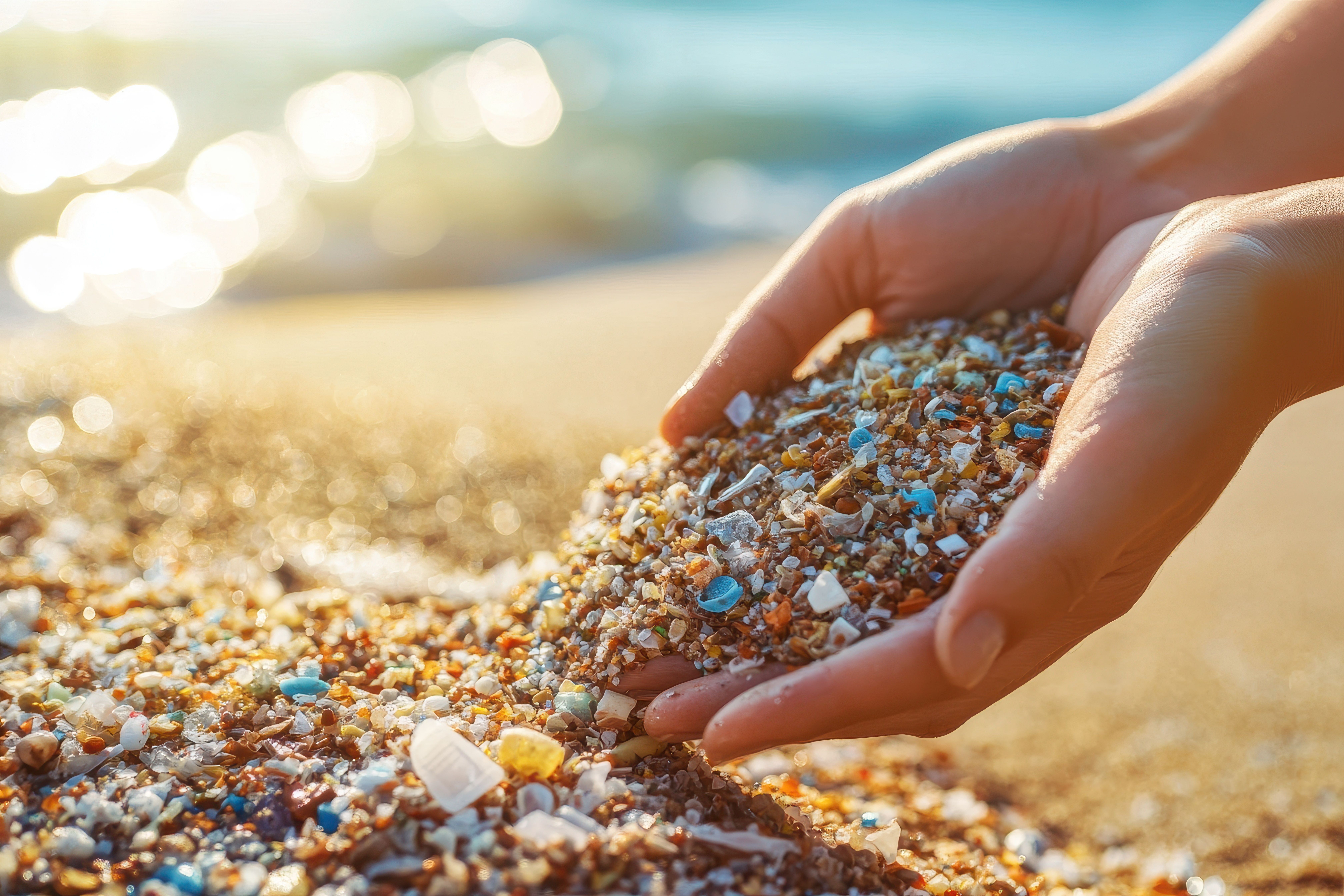 Hand scooping up a mixture of sand and microplastics from the shore, theme of pollution. Generated using AI. | Image Credit: © nabila - stock.adobe.com.