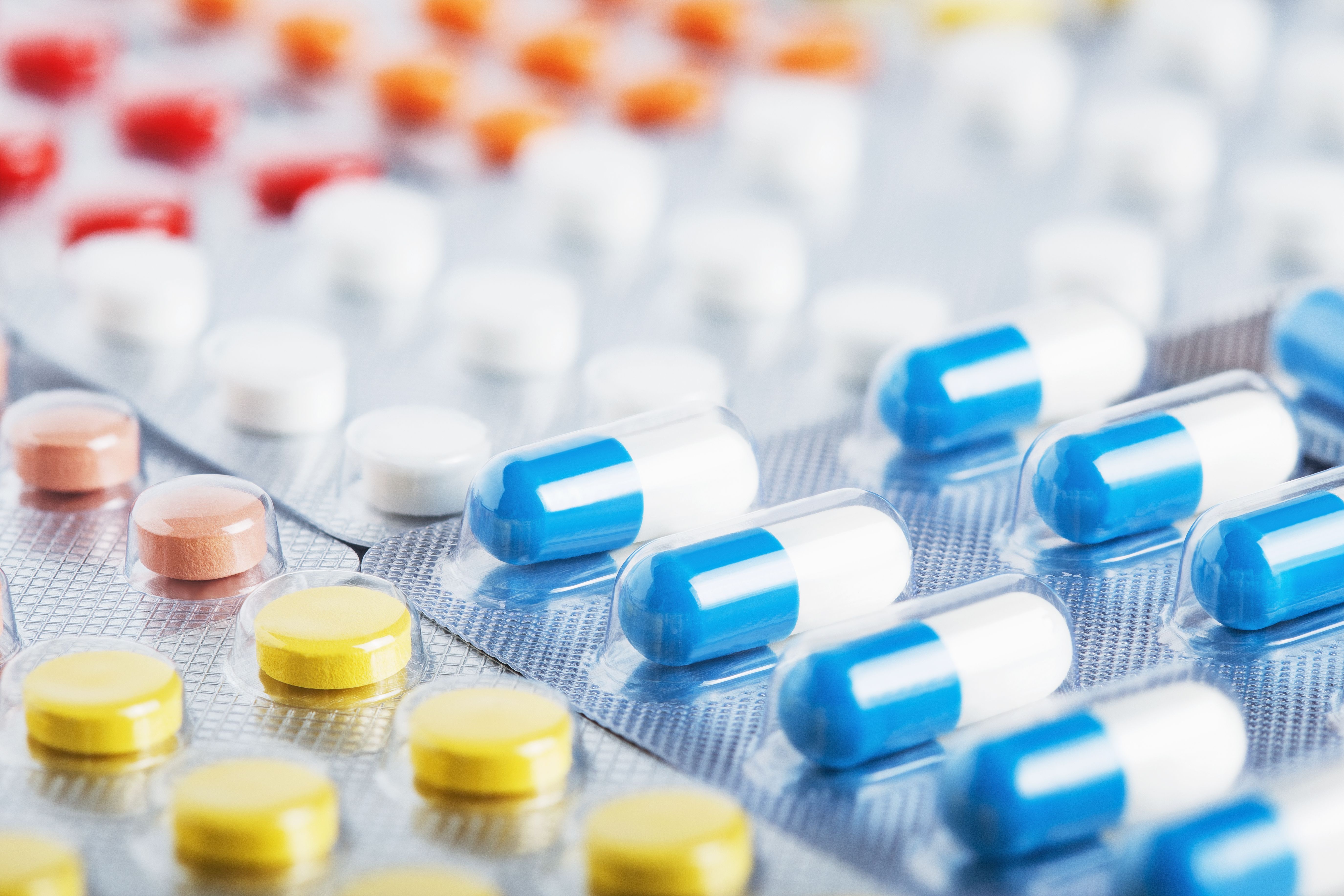 Heap of medical pills in white, blue and other colors. Pills in plastic package. Concept of healthcare and medicine. | Image Credit: okskaz - stock.adobe.com