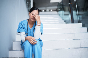 female doctor sitting on stairs head in her hands