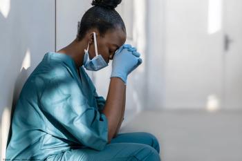 Tired doctor sitting against a wall 