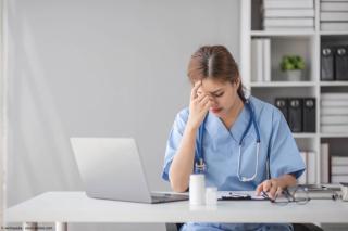 Stressed female doctor looking at laptop | Image Credit: © wichayada - stock.adobe.com