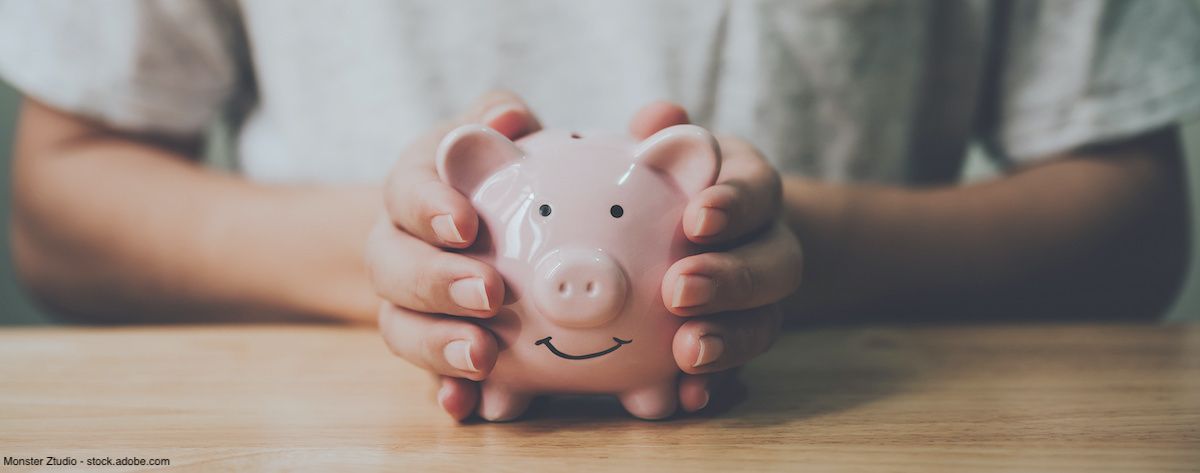 Man holding a piggy bank on a wooden table