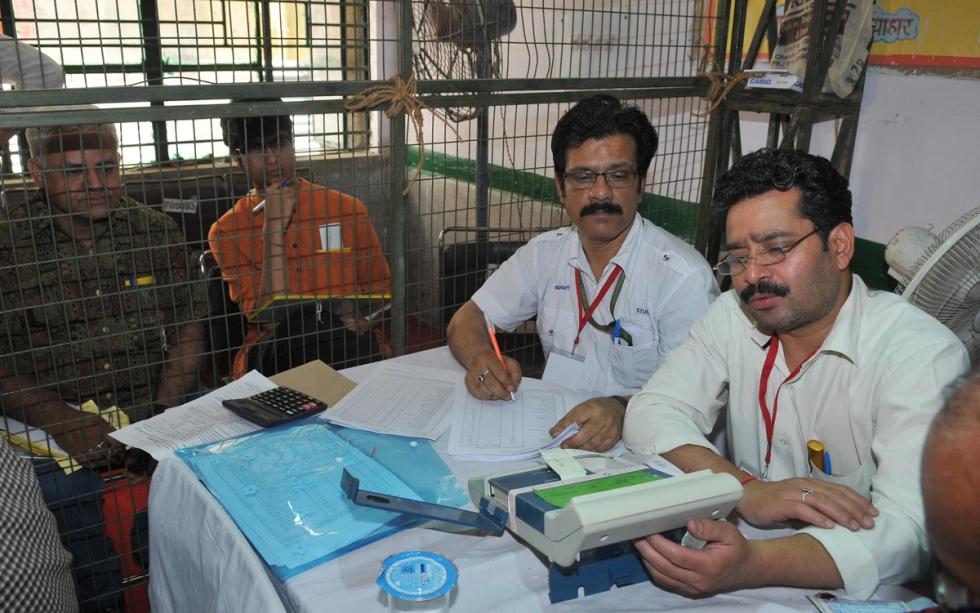 Election officials read results from an electronic voting machine at a counting centre in New Delhi