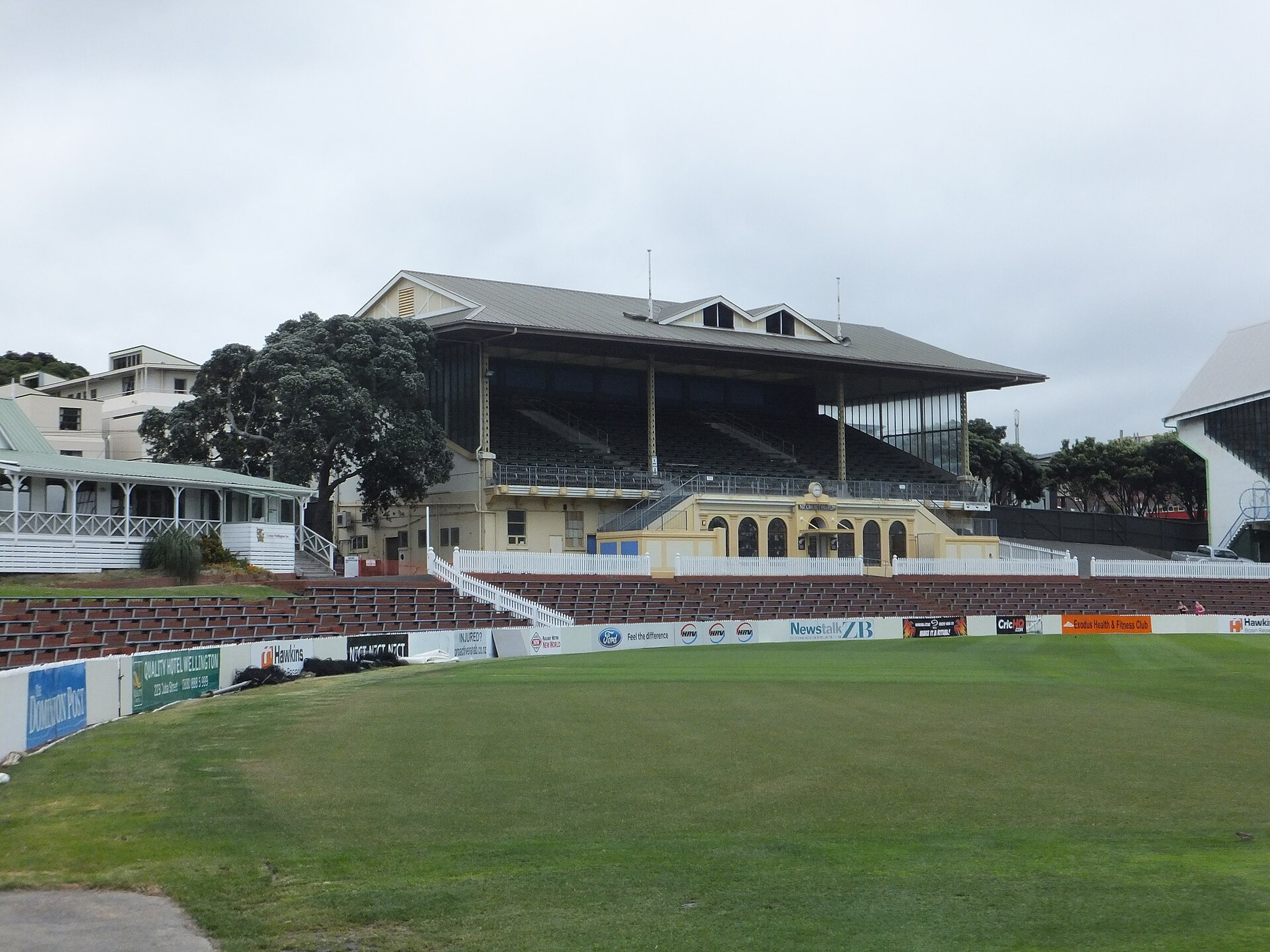 Grandstand and empty outfield at Basin Reserve cricket ground, with sponsor boards along the boundary wall.