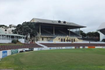 Grandstand and empty outfield at Basin Reserve cricket ground, with sponsor boards along the boundary wall.