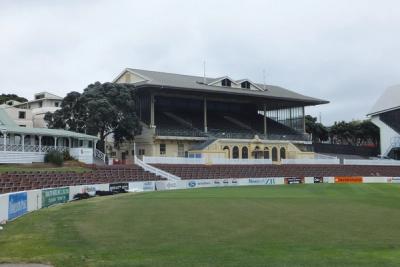Grandstand and empty outfield at Basin Reserve cricket ground, with sponsor boards along the boundary wall.