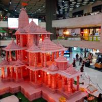 Miniature Ram Temple model on display in a New Delhi shopping mall, with shoppers on the floor and upper levels.