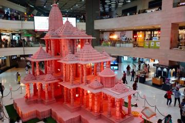 Miniature Ram Temple model on display in a New Delhi shopping mall, with shoppers on the floor and upper levels.