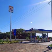 HP petrol station with a covered forecourt, fuel pumps and signboards under a clear blue sky.