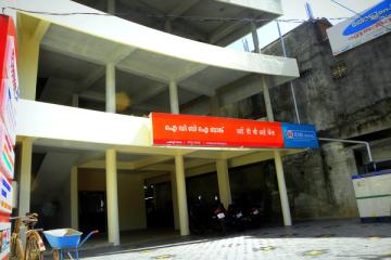 Exterior of an IDBI Bank branch with red and white signage, with motorbikes parked under a concrete building.