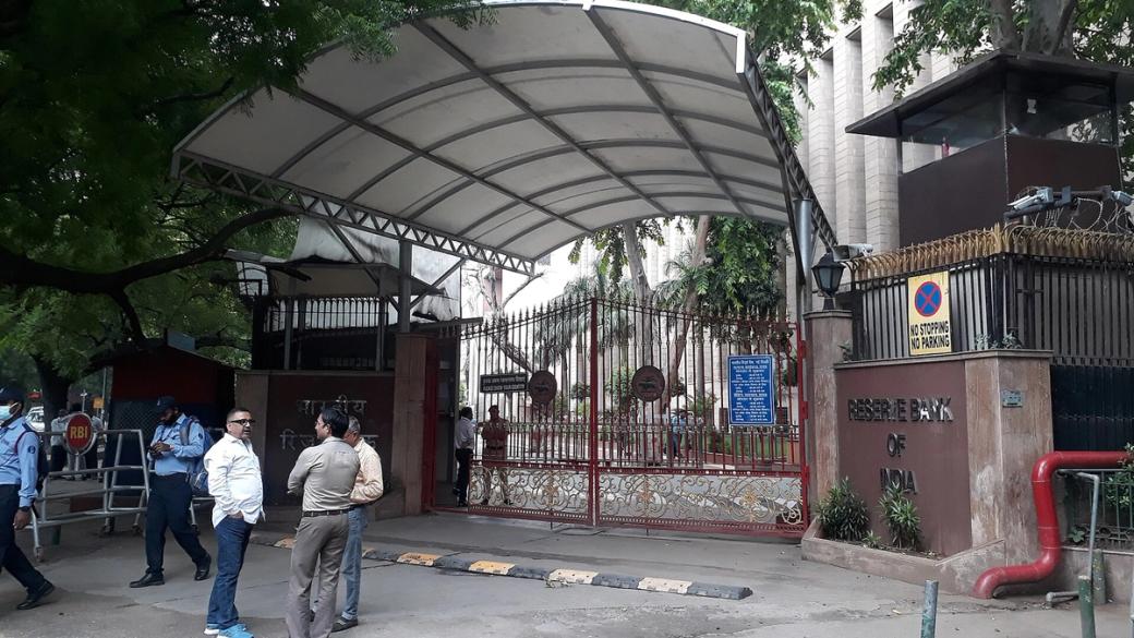 Reserve Bank of India building in New Delhi, with motorbikes and auto-rickshaws moving on the road in front.