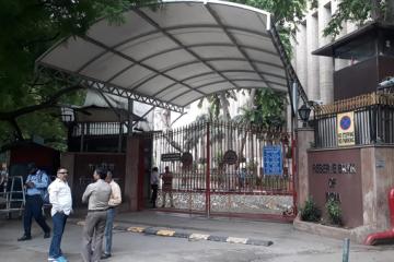 Reserve Bank of India building in New Delhi, with motorbikes and auto-rickshaws moving on the road in front.