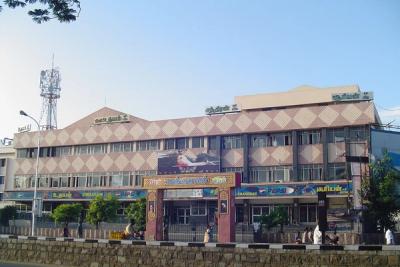 Facade of a multi-storey cinema hall with signboards, a film poster and pedestrians on the street
